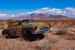 Photo of an old car wreck in a desert